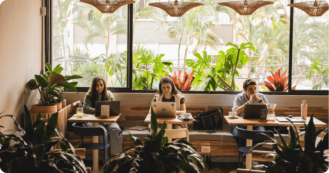 Personas trabajando con computadoras portátiles en una zona de escritorios compartidos.